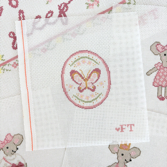 needlepoint butterfly with ditsy pink flowers inside an oval frame